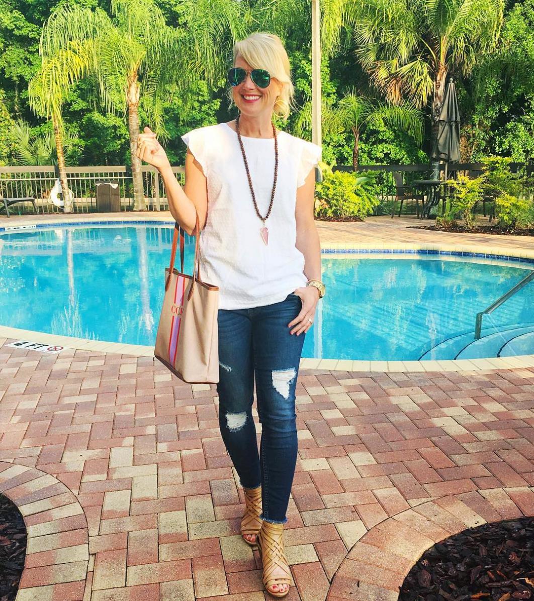 Smiling woman poolside with a stripe monogram purse